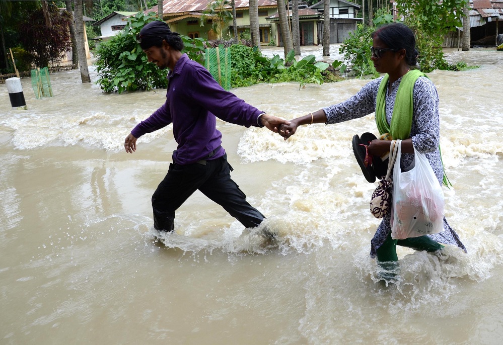 Villager waded through  water to safer place after the breach of Hatimura embankment in Nagaon district on Sunday. Pix by UB Photos