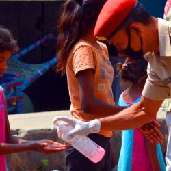 A policeman giving hand sanitizer to a young girl at road side in Guwahati