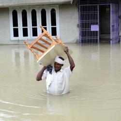 Villager waded through  water to safer place after the breach of Hatimura embankment in Nagaon district on Sunday. Pix by UB Photos