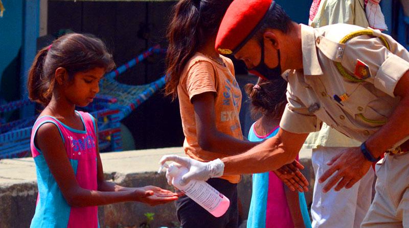 A policeman giving hand sanitizer to a young girl at road side in Guwahati