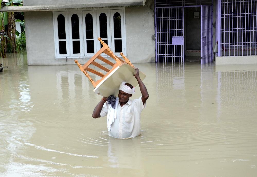 Villager waded through  water to safer place after the breach of Hatimura embankment in Nagaon district on Sunday. Pix by UB Photos